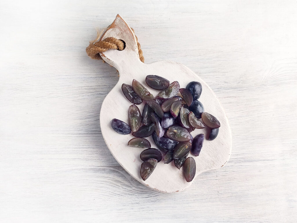 Cut grapes on a cutting board.
