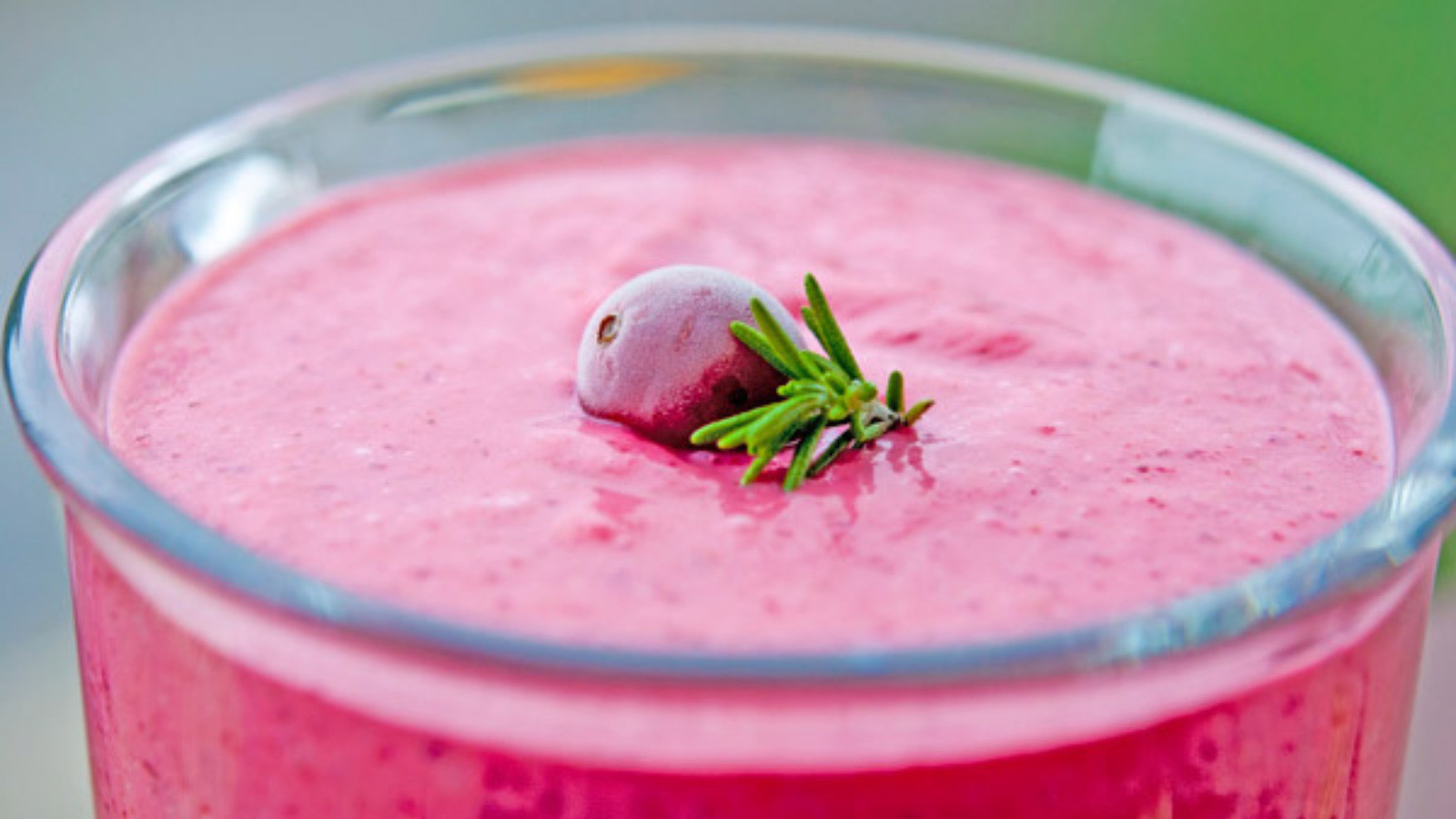 Side view of a glass mug filled with cranberry banana smoothie.