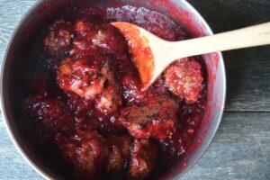 Meatballs in a pot, coated in cranberry glaze.