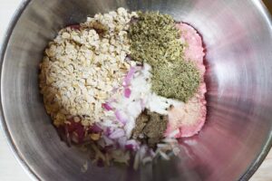 Meatball ingredients added to a mixing bowl.