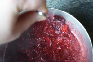 Smashing cranberries as they cook in a pot with a fork.