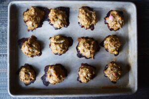 Baked meatballs lined up on a baking sheet.