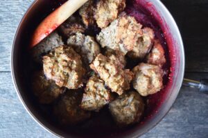 Baked turkey meatballs added to a pot of cranberry glaze.