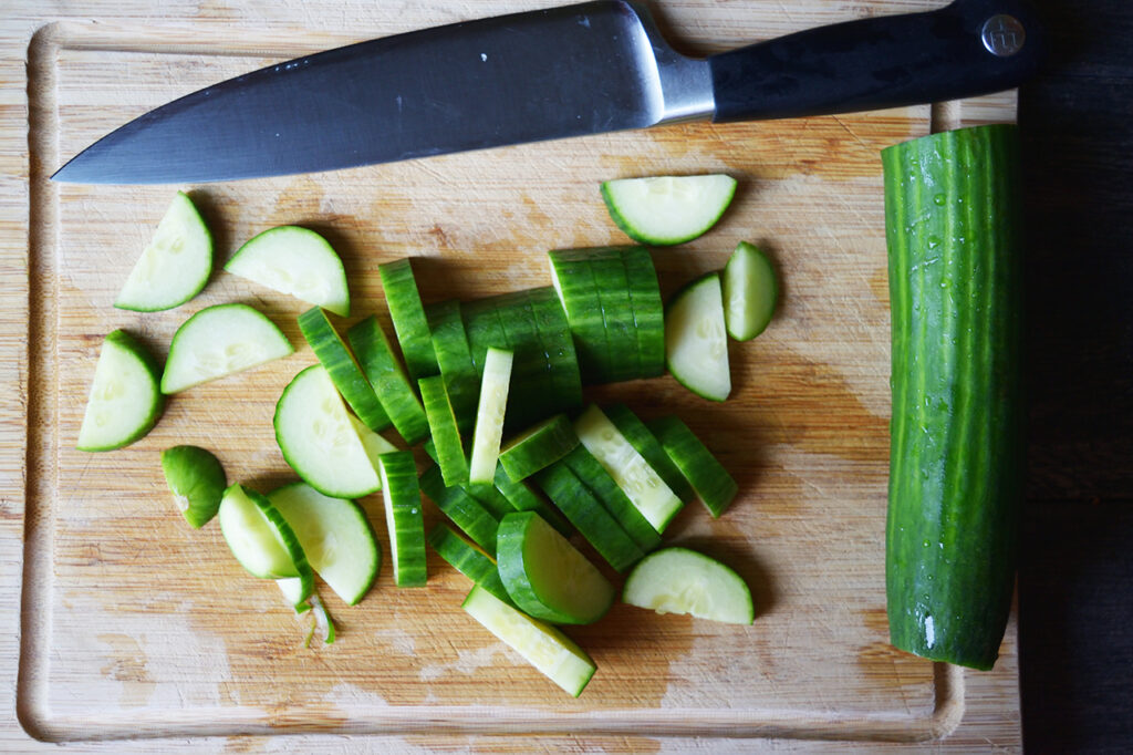 Sliced cucumbers on a cutting board with a knife.