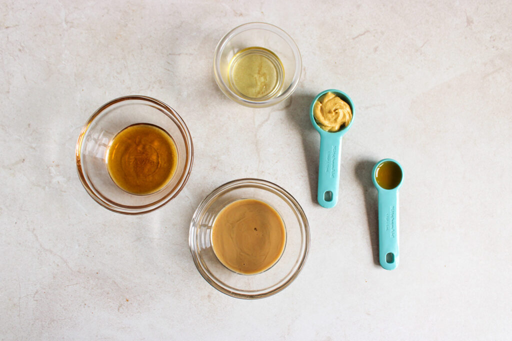 Tahini dressing ingredients sitting on a white surface.