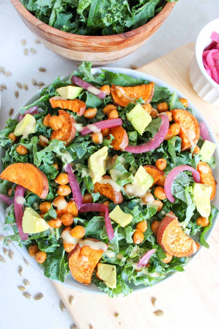 A fall harvest salad in a white bowl with tahini dressing drizzled over the top of the salad.