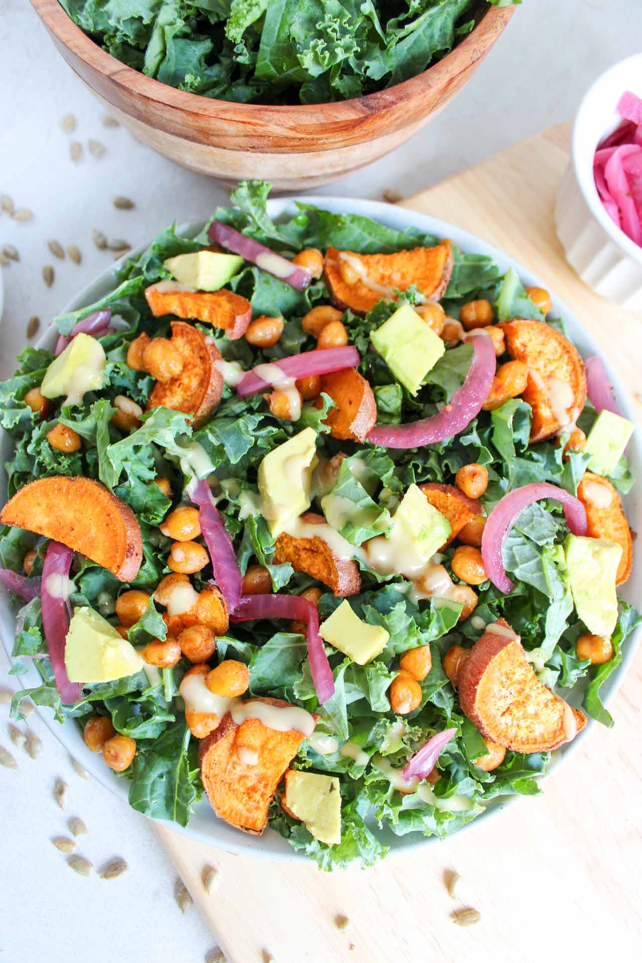 A fall harvest salad in a white bowl with tahini dressing drizzled over the top of the salad.