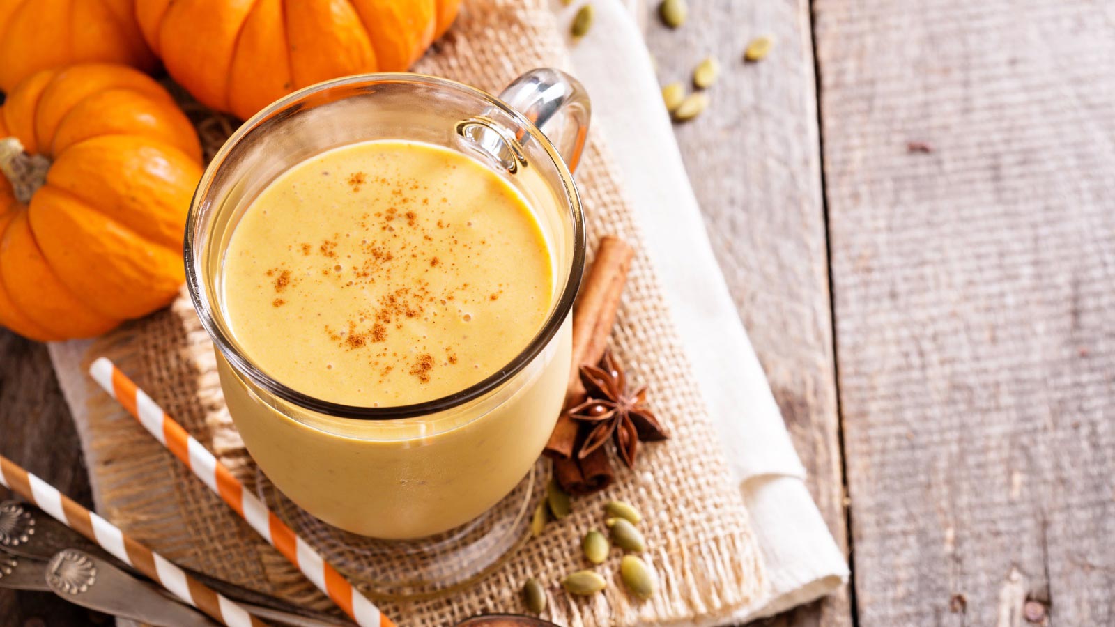 Healthy pumpkin smoothie in big mugs on rustic background