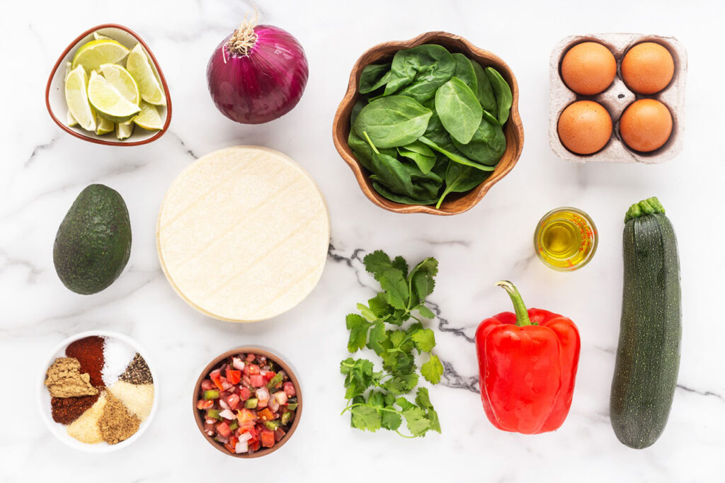 Ingredients for healthy breakfast tacos on a white surface.