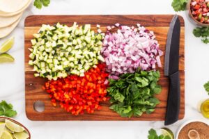 Chopped vegetables on a wood cutting board with a knife.