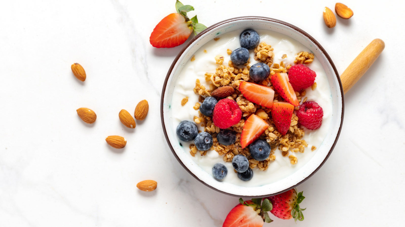 Healthy breakfast bowl with ingredients granola fruits Greek yogurt and berries top view.