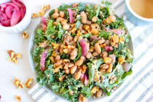 Overhead view of a white bowl filled with Kale Salad With Walnuts And Butter Beans.