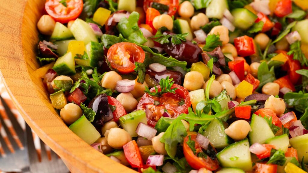A closeup of a wood salad bowl filled with Mediterranean chopped salad.
