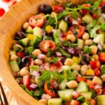 Side view of a wood salad bowl filled with Mediterranean chopped salad.