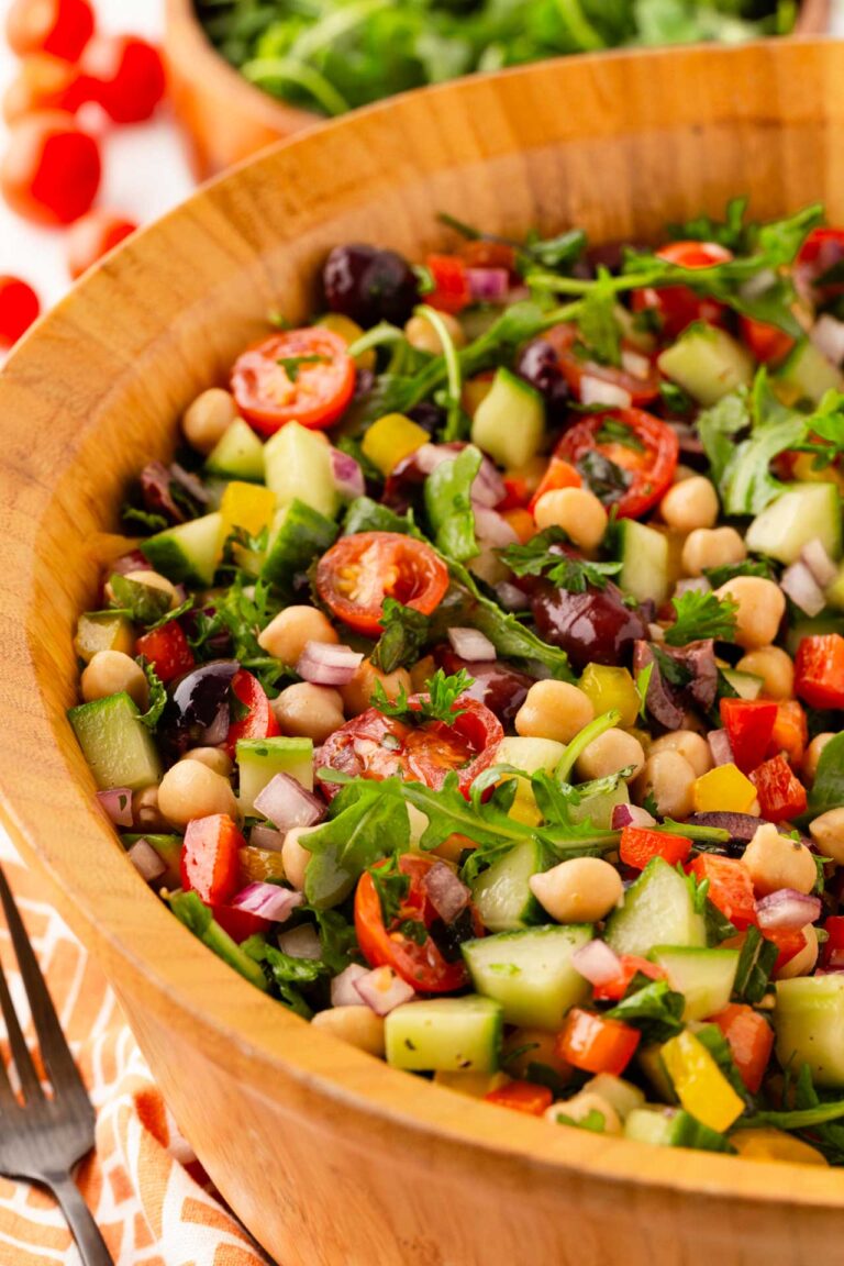 Side view of a wood salad bowl filled with Mediterranean chopped salad.