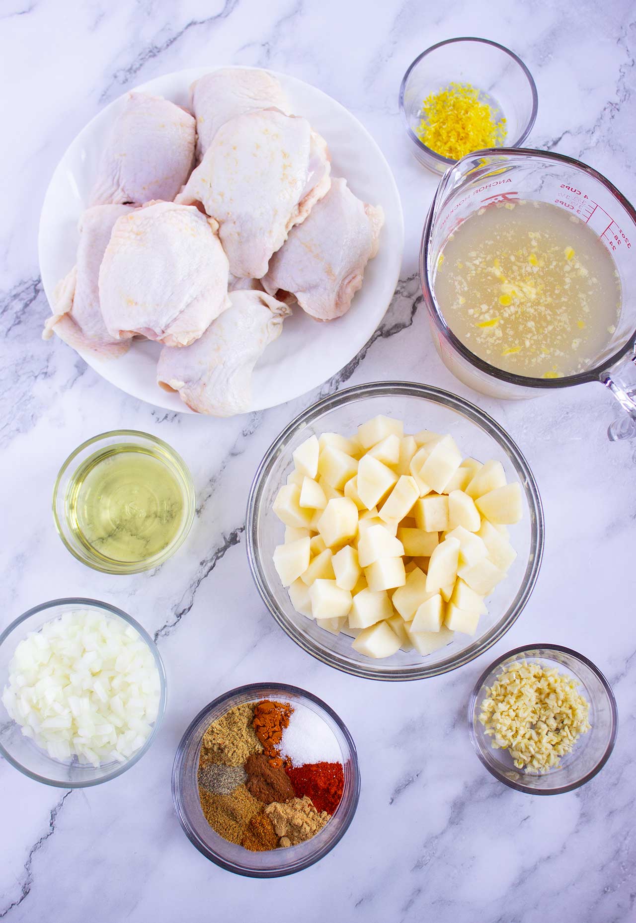 Ingredients for Moroccan chicken on a white, marble surface.