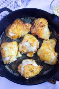Browned chicken pieces in a skillet.