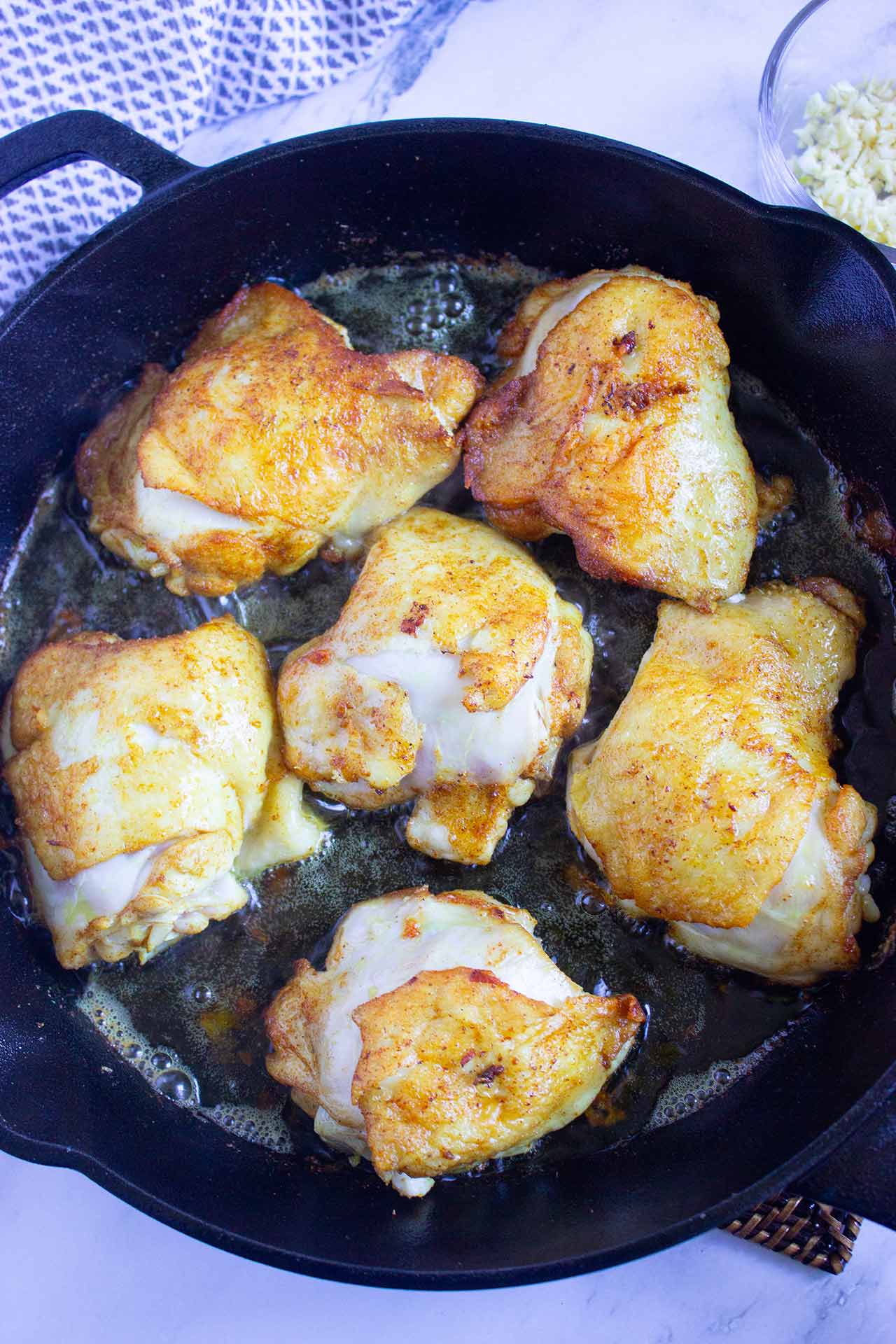 Browned chicken pieces in a skillet.