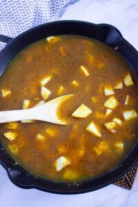 Brown sauce in a skillet with cut potatoes.