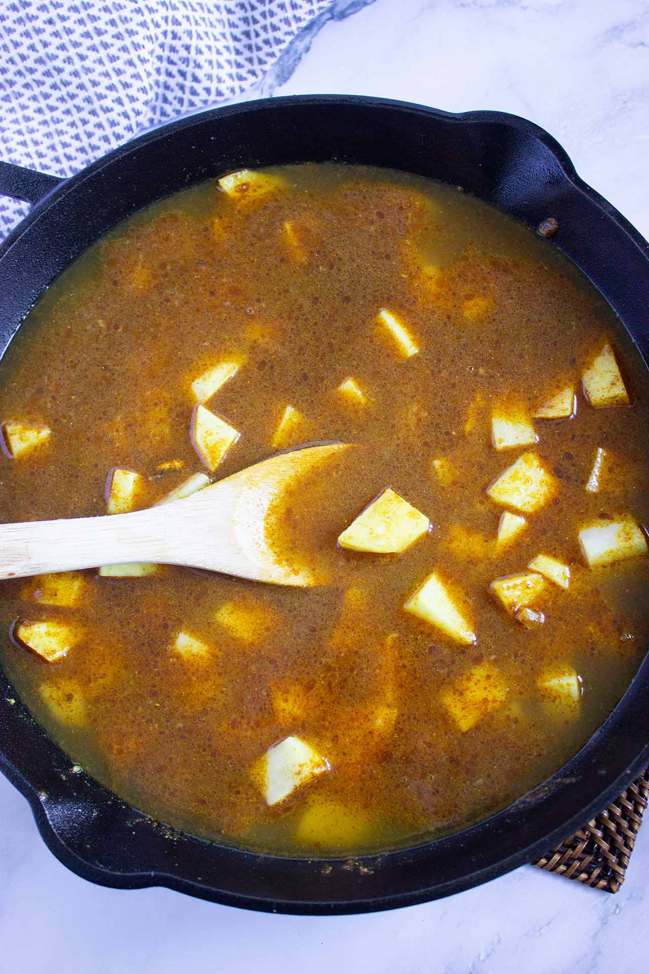 Brown sauce in a skillet with cut potatoes.