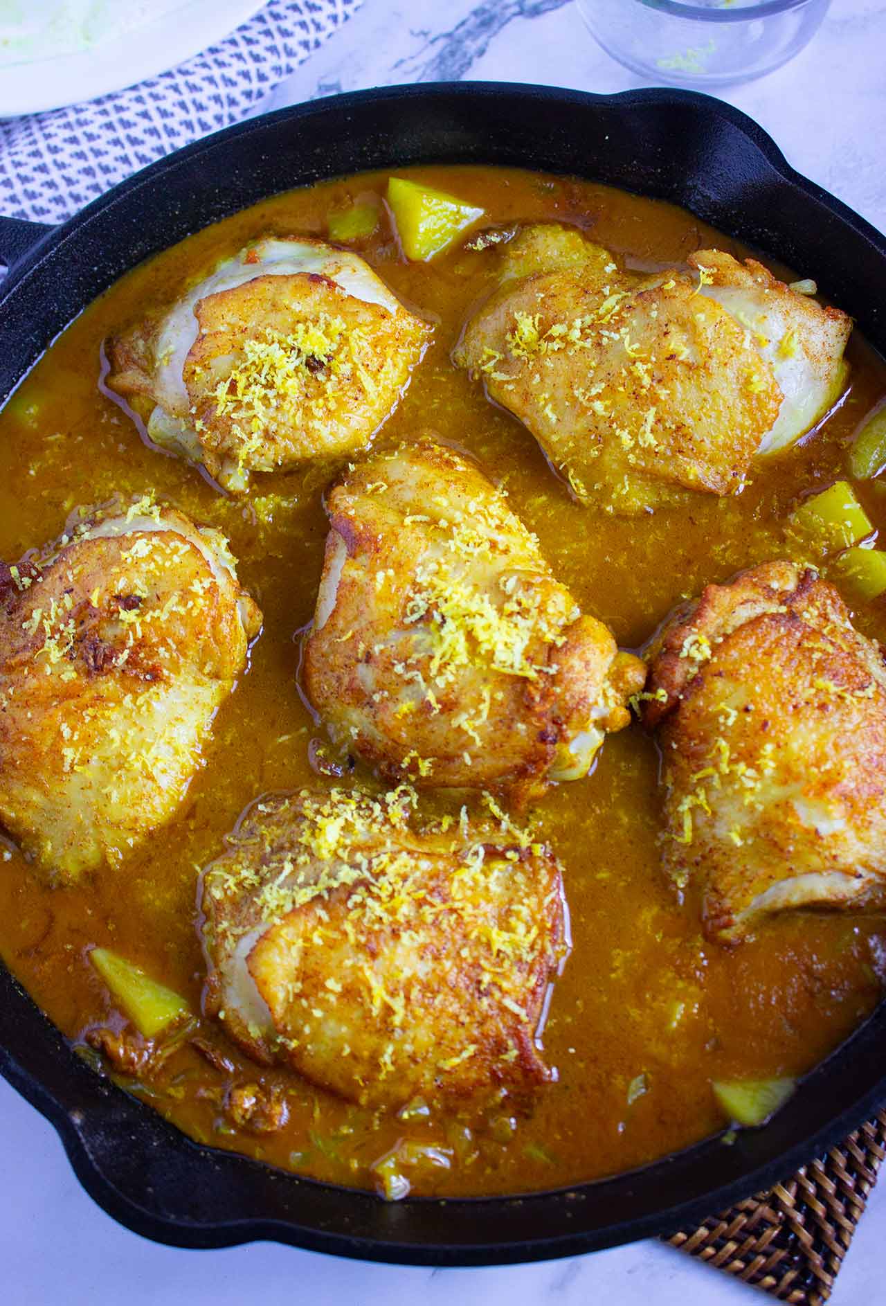 A skillet full of seasoned chicken pieces in sauce.