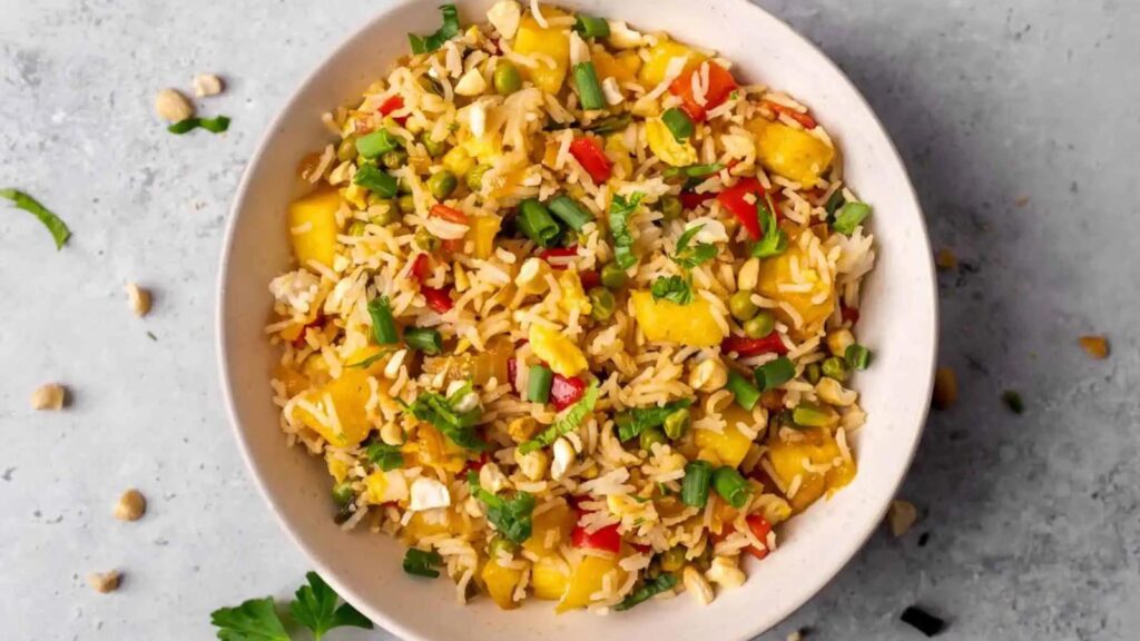 An overhead view of a white bowl filled with pineapple fried rice.