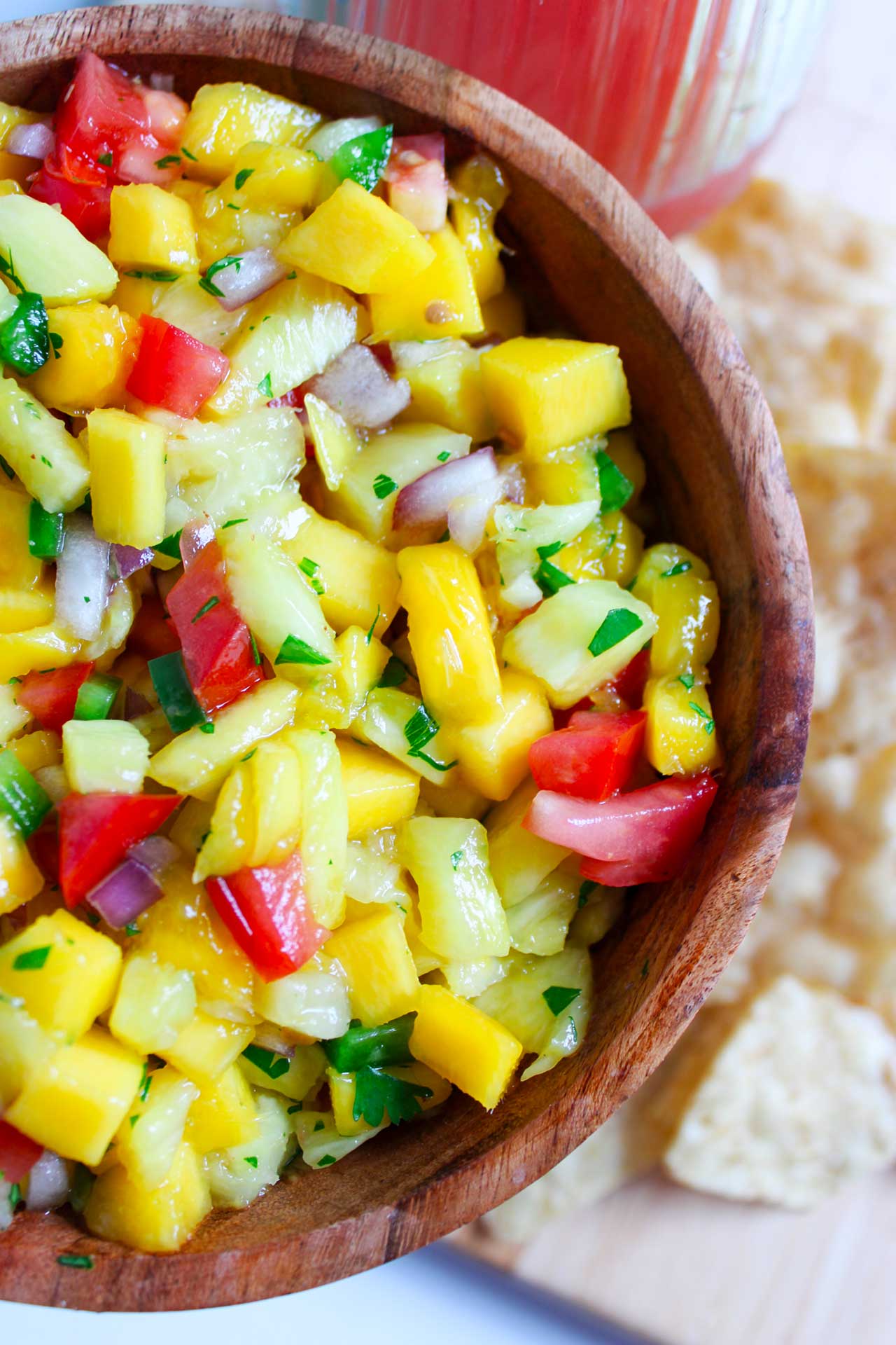Partial overhead view of a wood bowl filled with Pineapple Mango Salsa.