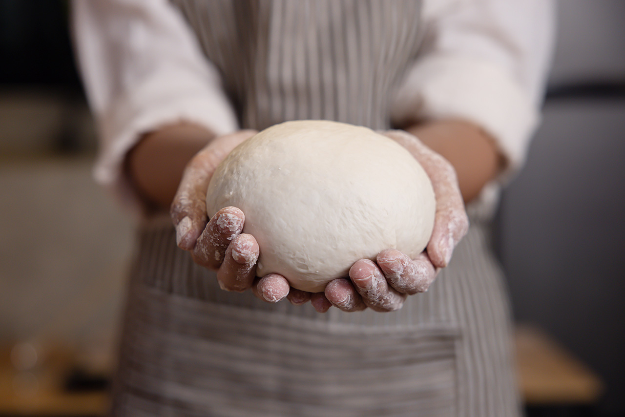 Woman's hands hold a ball of dough.