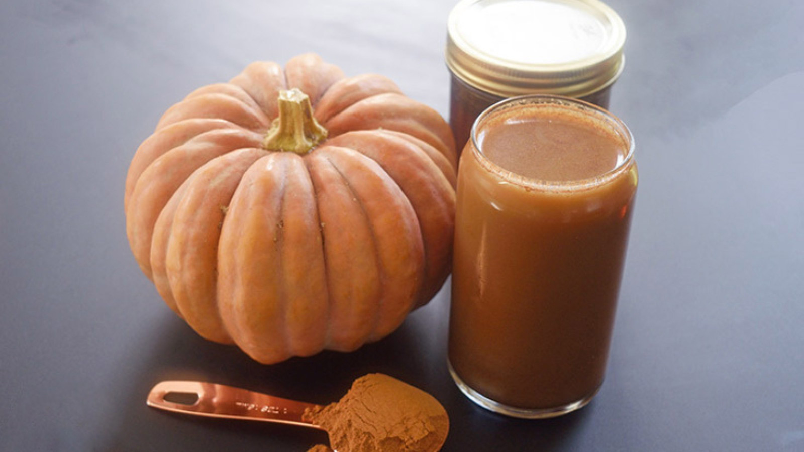 Pumpkin Spice Cold Brew Coffee in a glass next to a pumpkin.