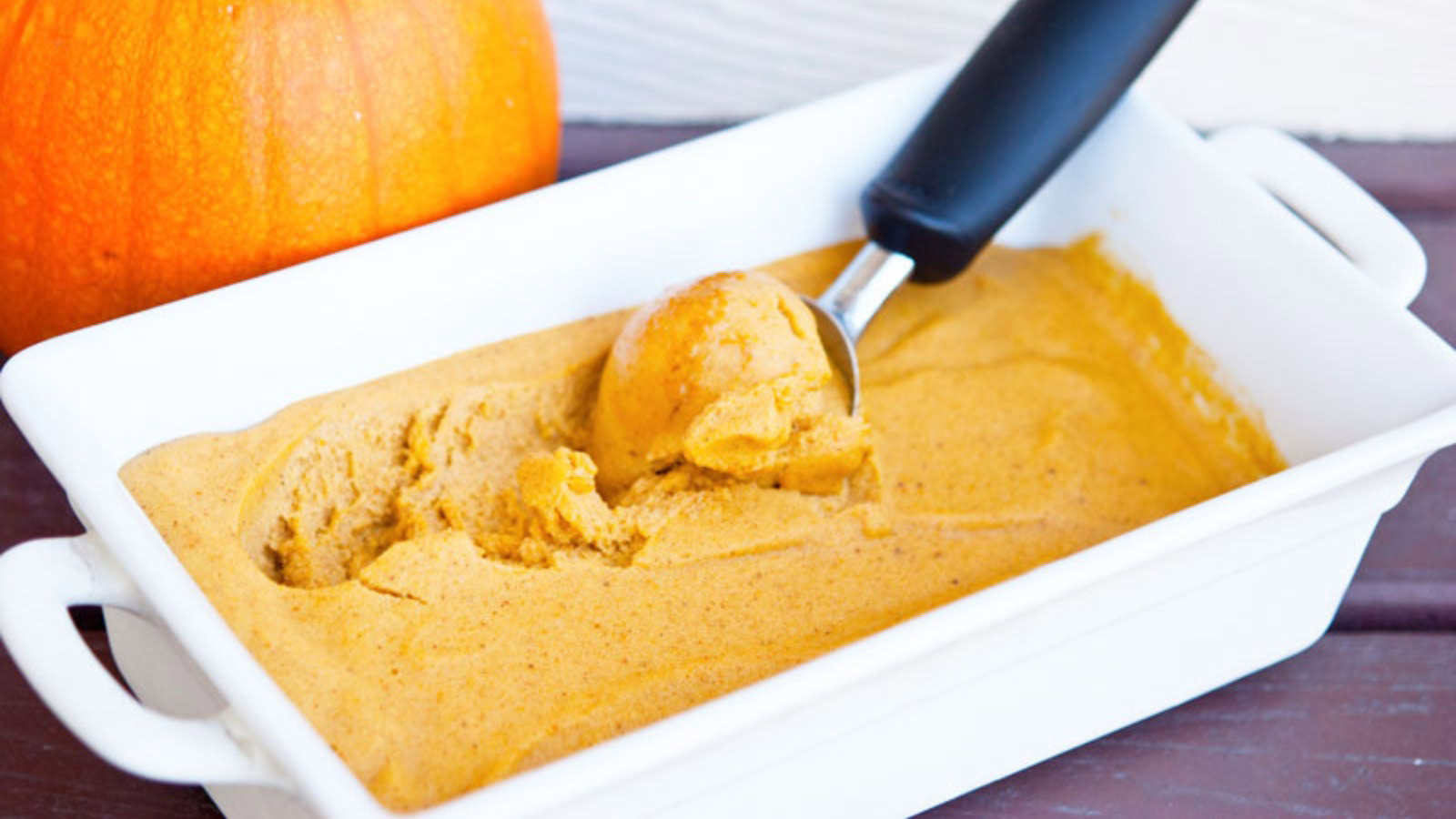 Pumpkin N'ice Cream being scooped out of a white casserole dish.