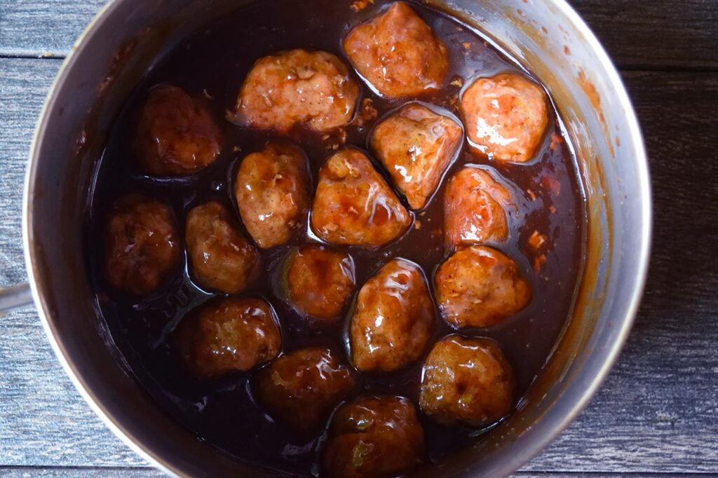 Meatballs in a pot of glaze, mixed together.