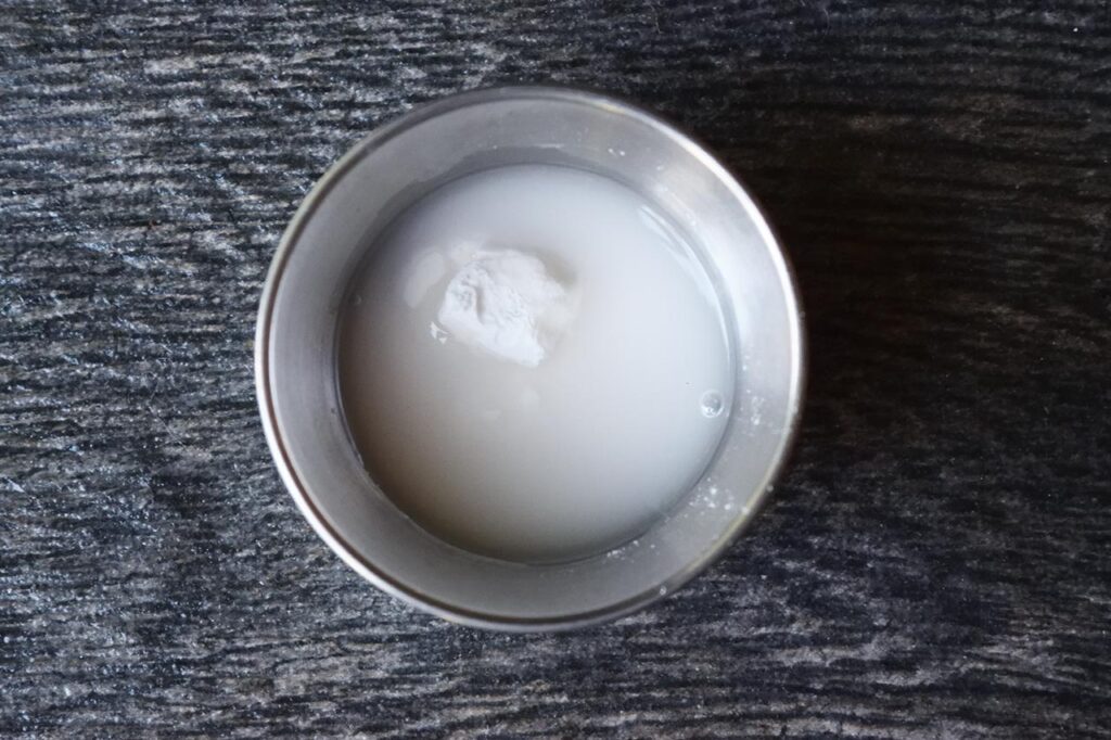 A slurry of water and arrowroot powder in a small, metal bowl.