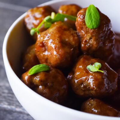 A side view of a bowl of glazed, Sweet And Sour Meatballs.