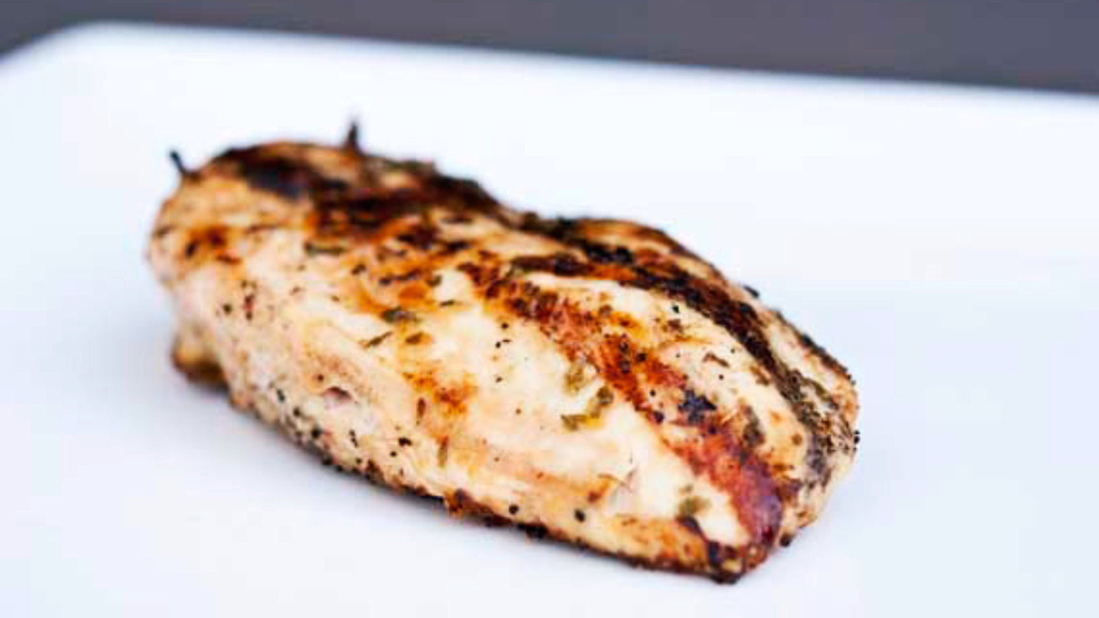 A single BBQ Tarragon Chicken breast on a white platter.