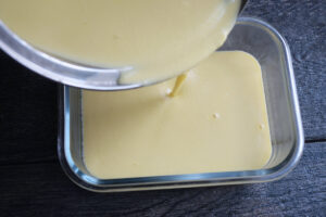 Transferring the custard to a freezer-safe container for cooling.