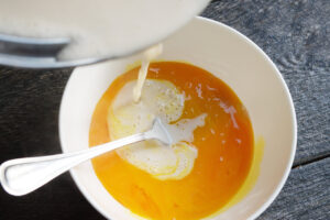 Tempering eggs with heated coconut milk mixture.