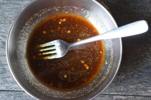 Thai cucumber salad dressing mixed together in a small, metal, mixing bowl.
