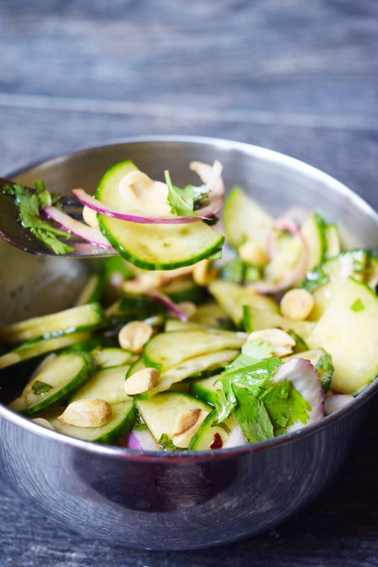 A fork lifts a bit of Thai cucumber salad. from a bowl.