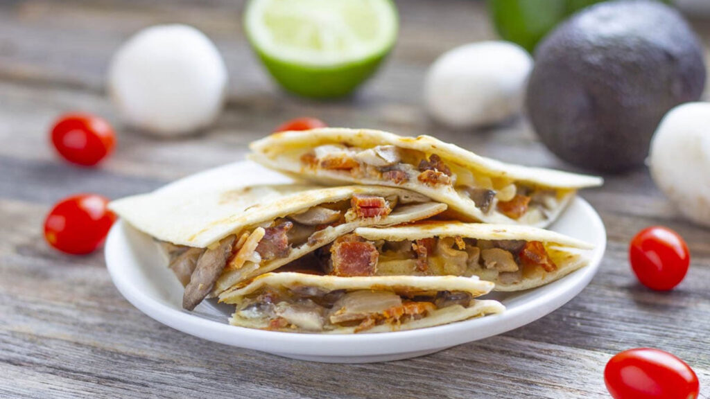 A white plate holds a pile of bacon quesadillas.