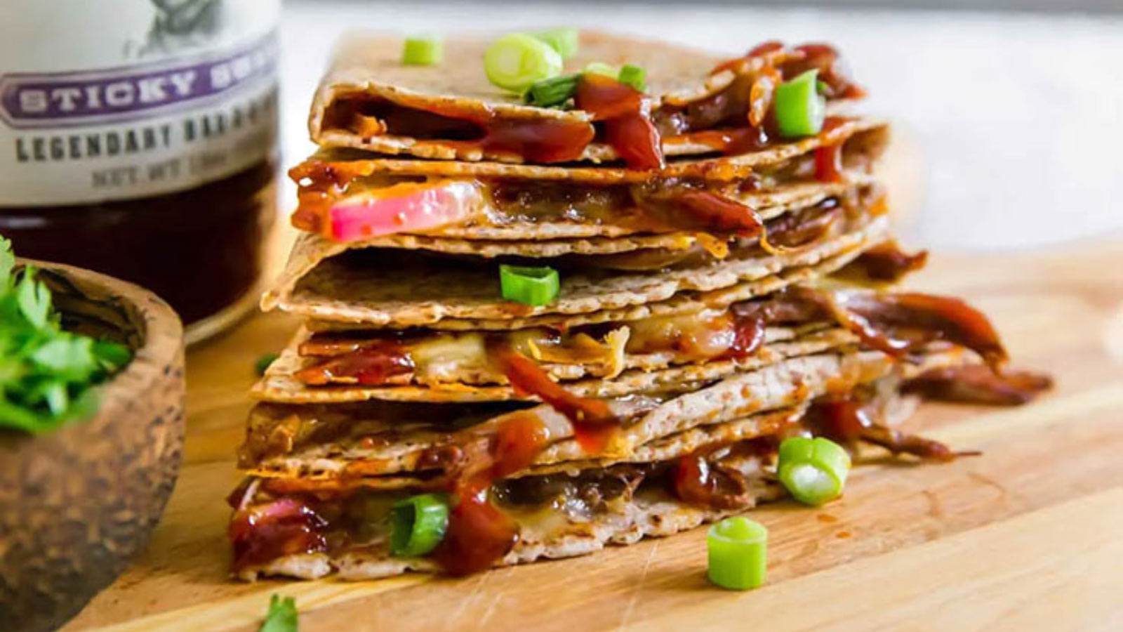 A pile of cut brisket quesadilla triangles on a cutting board.