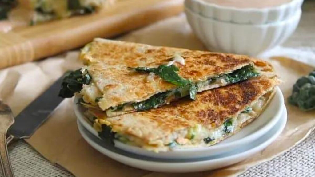 A cut kale quesadilla on a white plate.