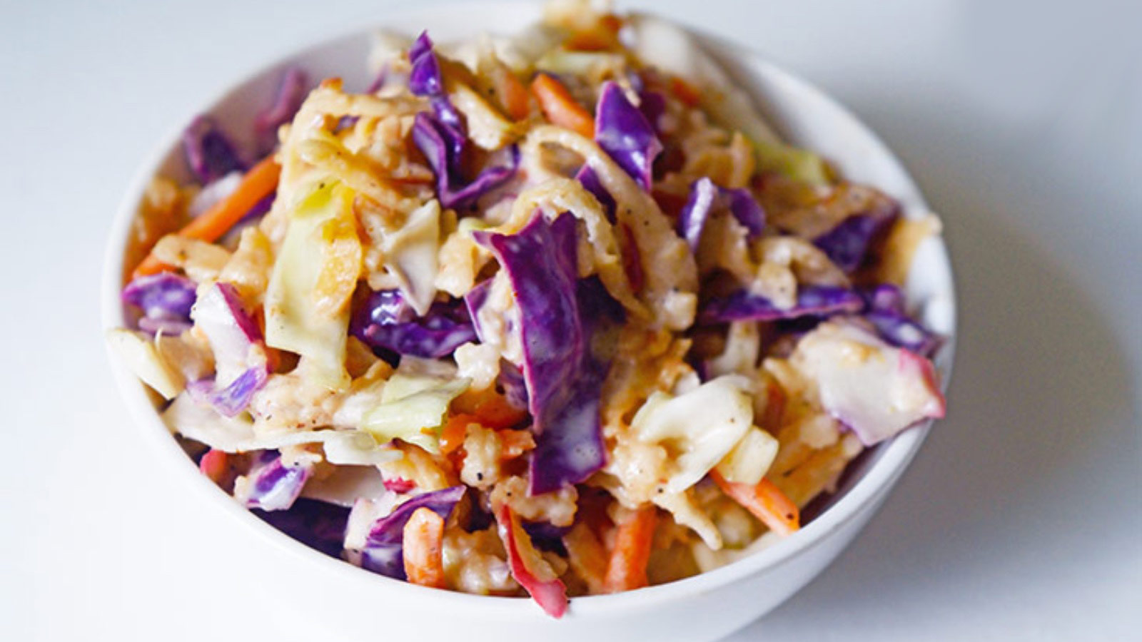 The finished Apple Slaw Recipe in a white bowl on a white background.