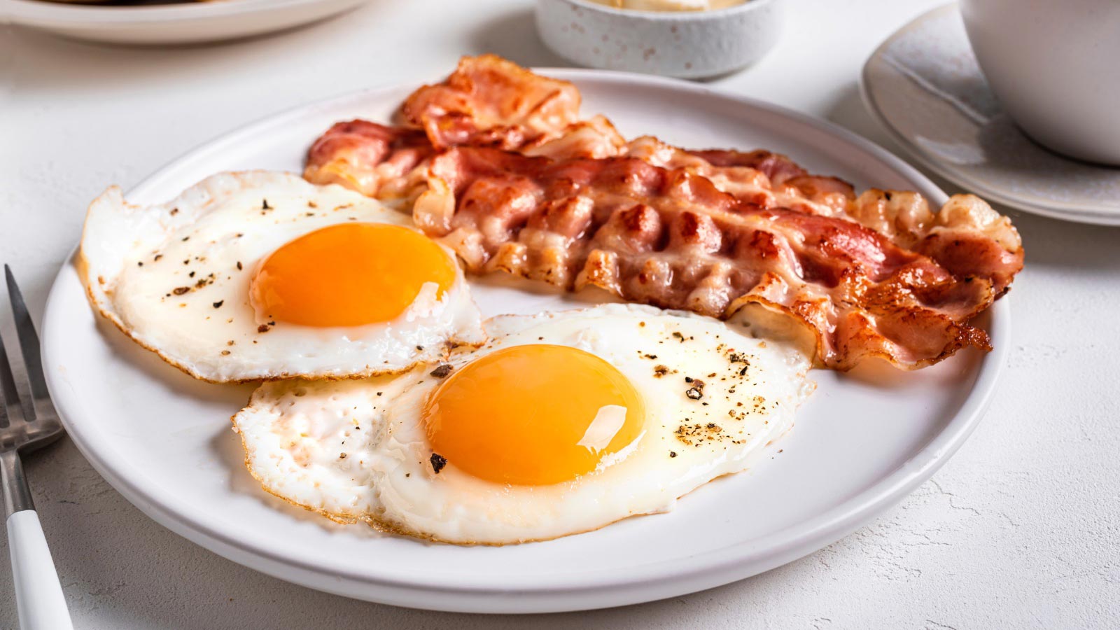 Breakfast with fried eggs and bacon close up. Fried sunny side eggs with bacon on plate.