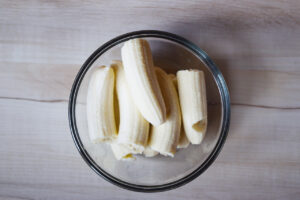 Halved bananas in a glass mixing bowl.