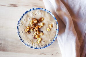 Banana pudding in a decorative bowl, topped with walnuts.