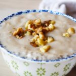 Front view of a decorative bowl filled with banana pudding, topped with walnuts.