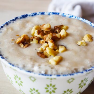 Front view of a decorative bowl filled with banana pudding, topped with walnuts.