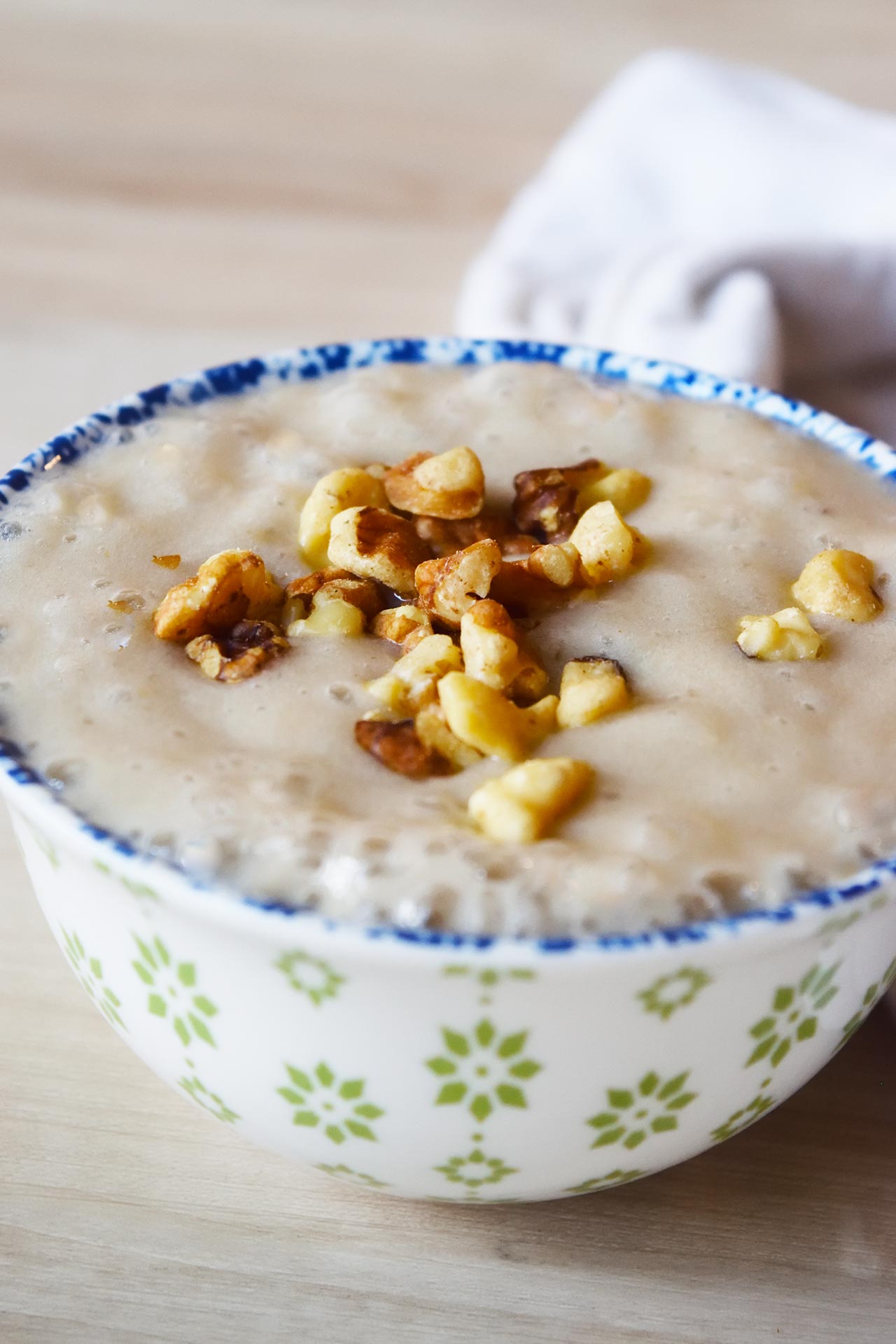 Front view of a decorative bowl filled with banana pudding, topped with walnuts.