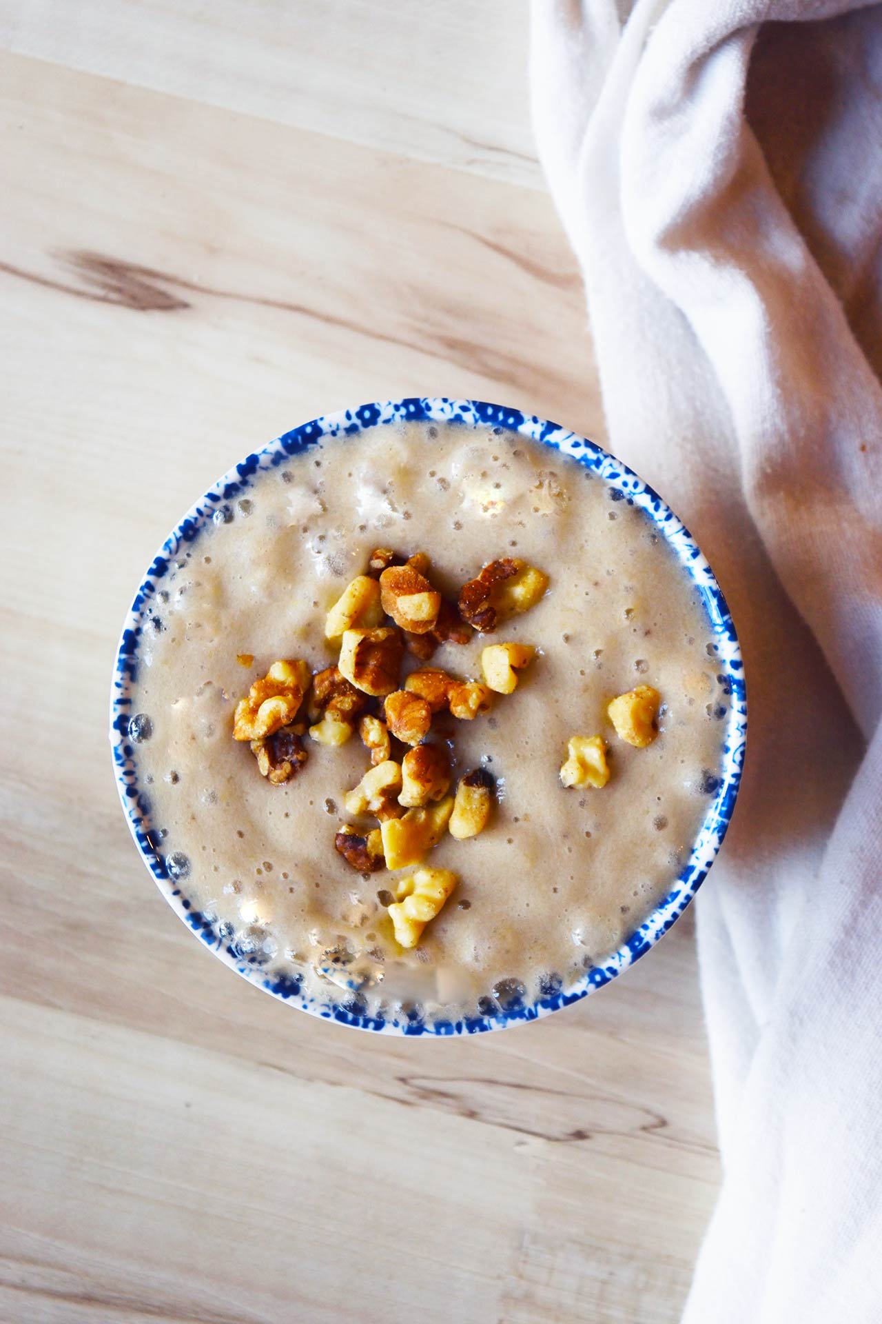 Overhead view of a bowl filled with banana pudding topped with walnut pieces.