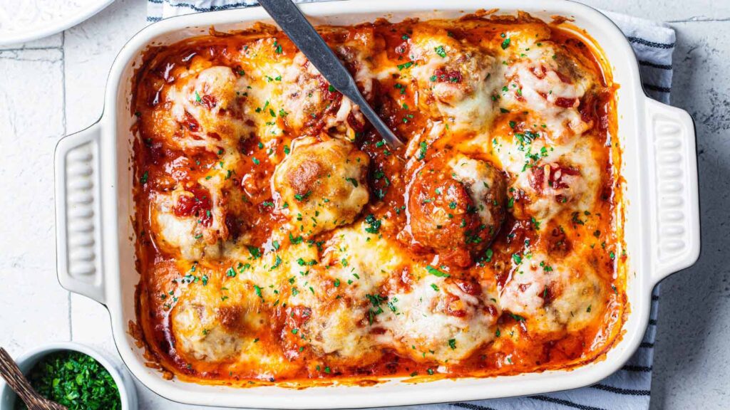 Baked cheesy meatballs casserole with tomato sauce in the oven dish.